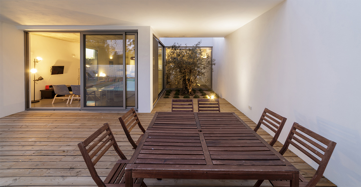 Moderner Terrassenbereich mit Holzdeck, Glasfassade und stilvollem Innenhof mit Baum – hochwertige Glasbau-Lösung von Barth & Ege.
