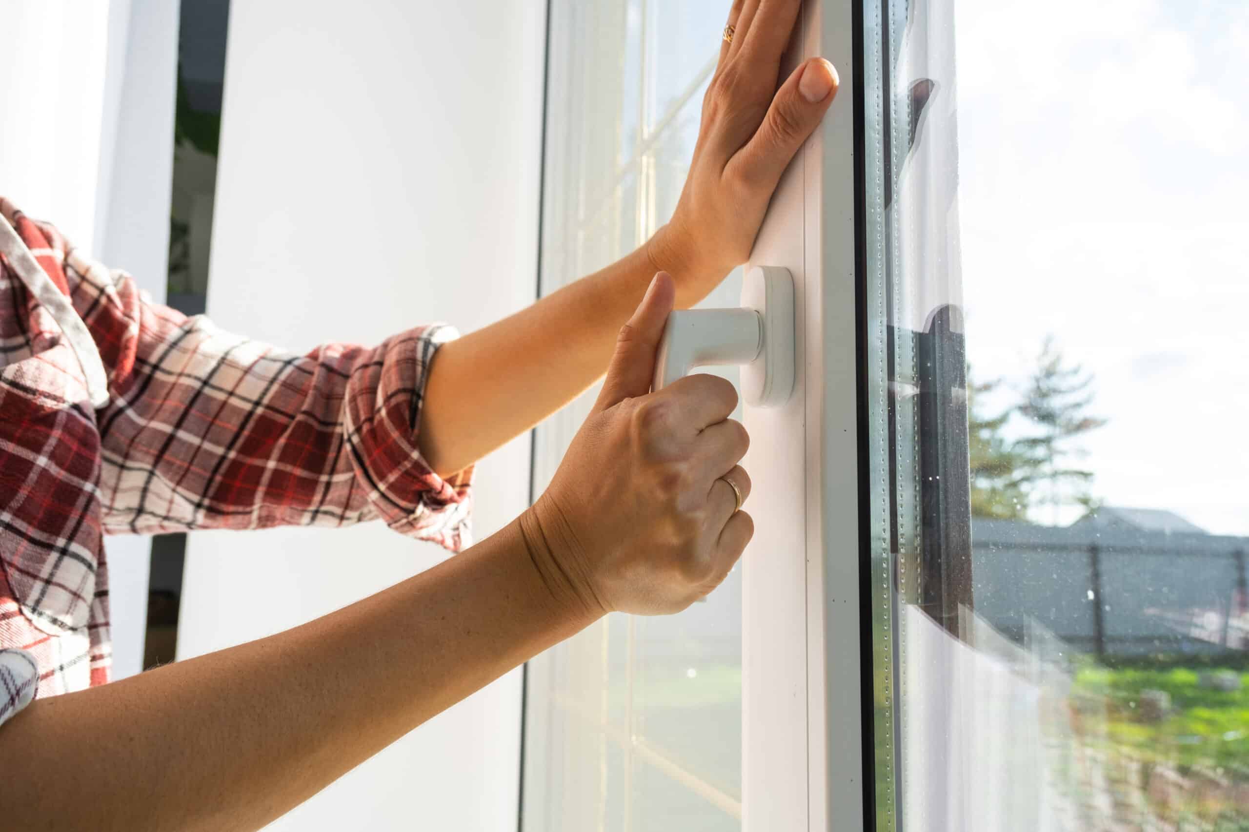 Person öffnet ein modernes Kunststoff-Fenster
